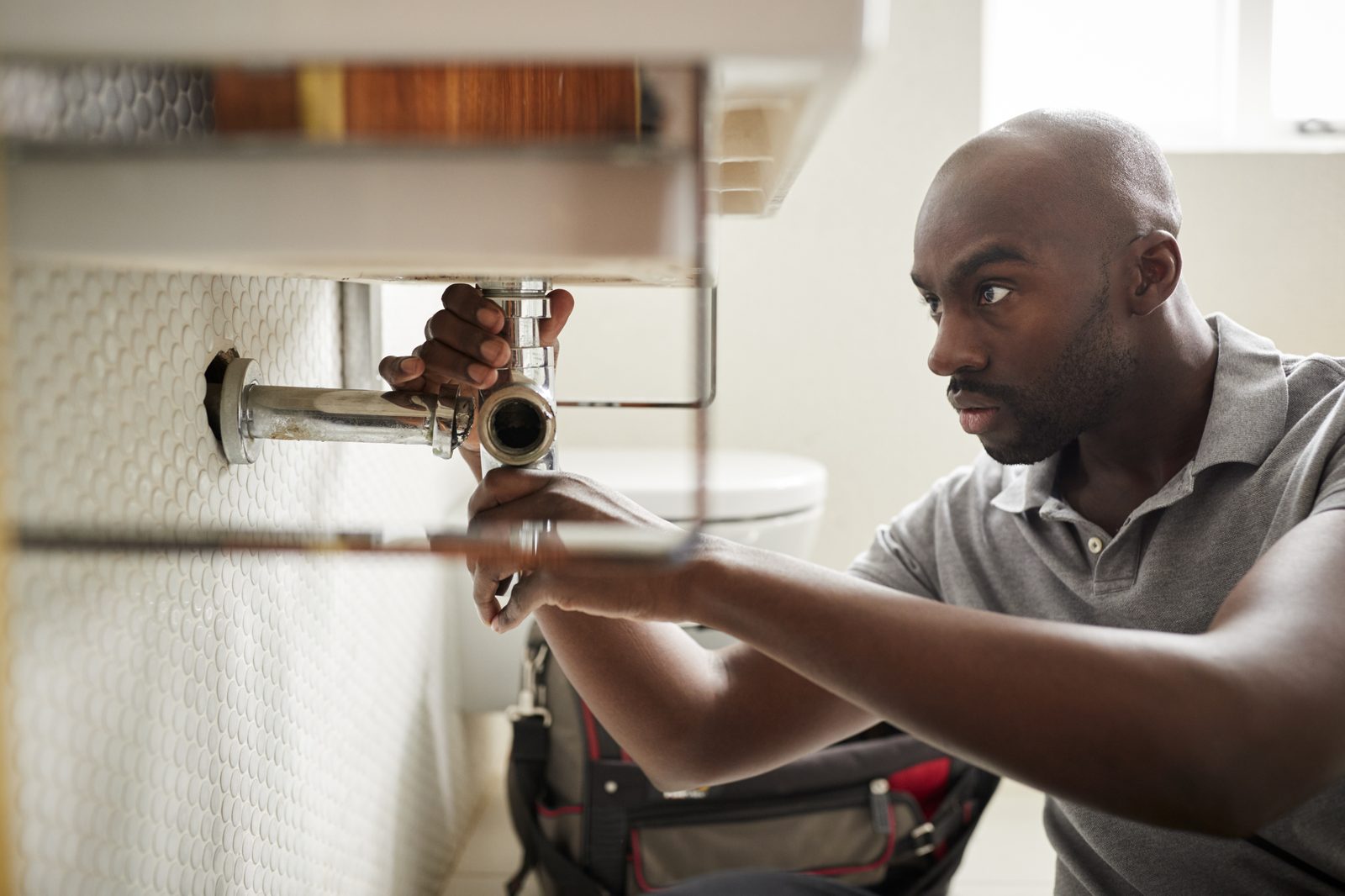 A plumber repairing pipework under a sink